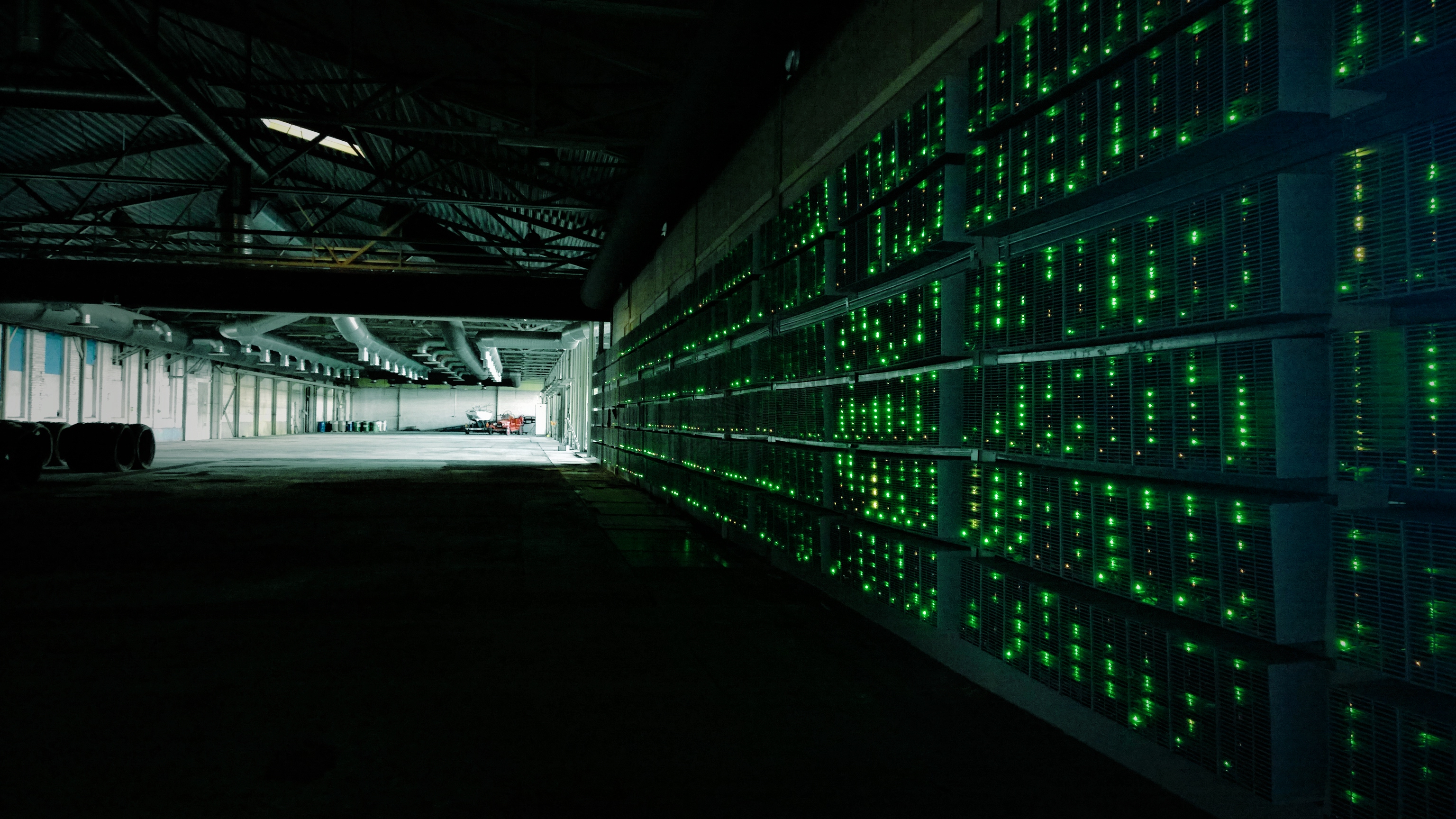 Rows of mining hardware with green status lights inside a large industrial building, photographed in 2014